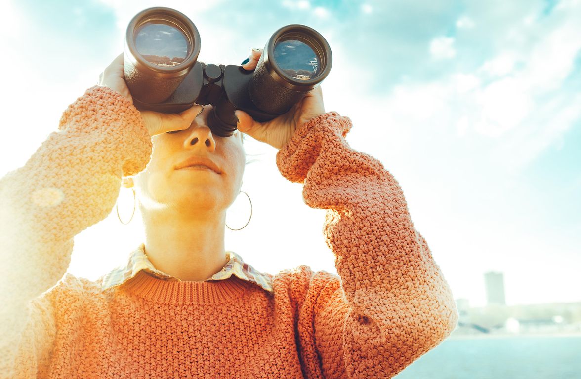 woman looks through binoculars to the future, our wealth planning services help plan for the future