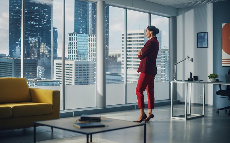 Woman in red suit staring outside window