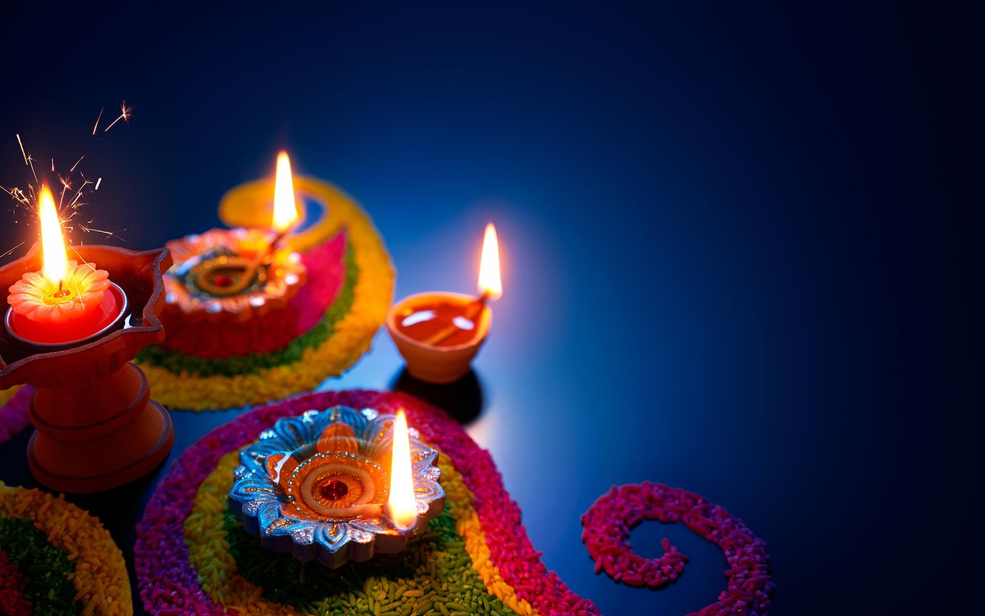 burning candles against colourful patterns 