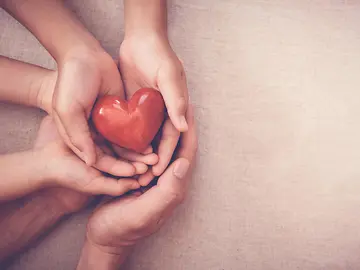 hands holding a wooden heart