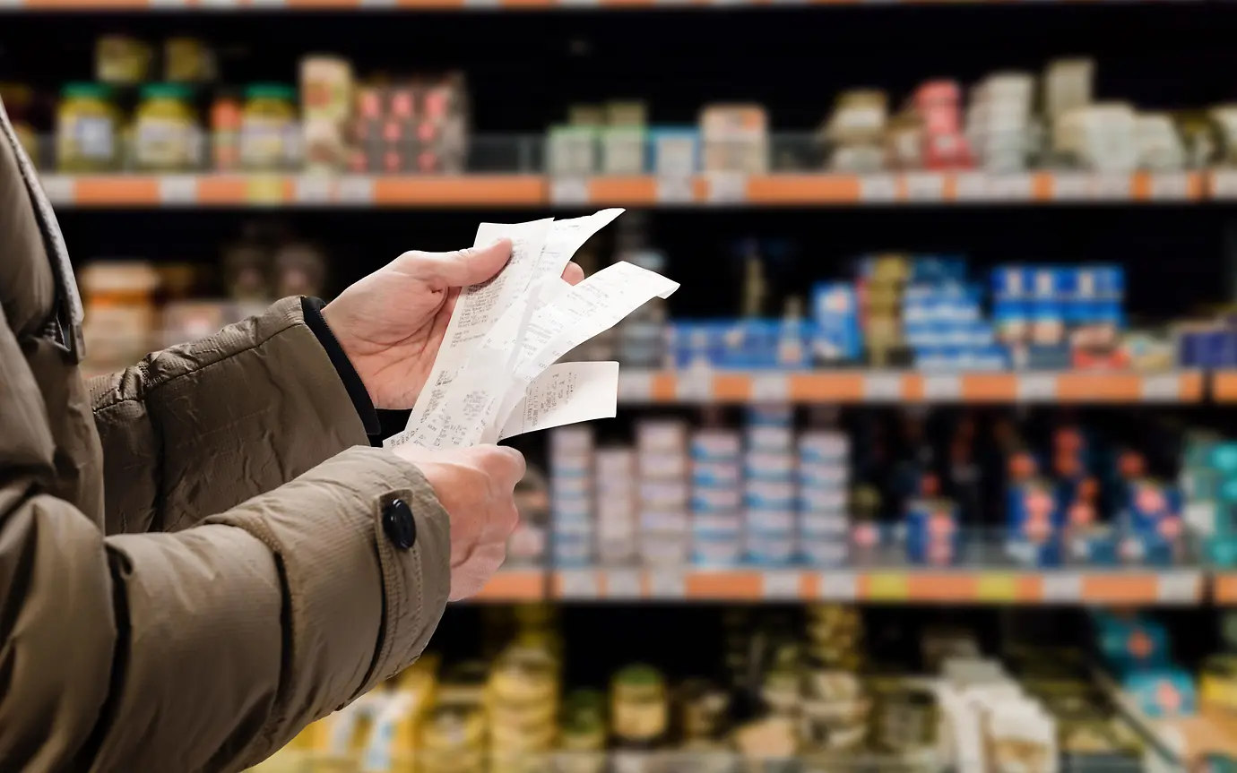 person standing in supermarket checking receipts