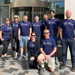 A group of staff from LGT Wealth Management, standing outside of the office in branded t shirts.