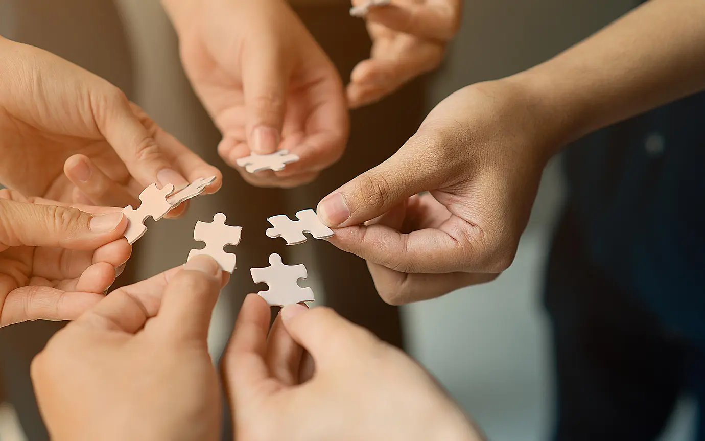Hands with jigsaw join together as team
