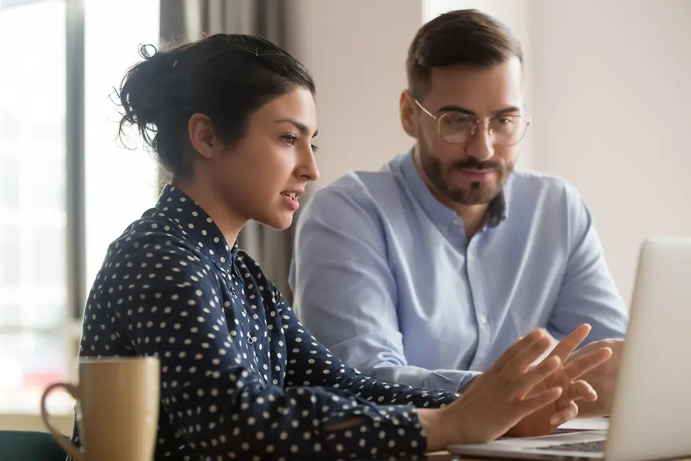Focused male to serious business woman mentor looking at laptop