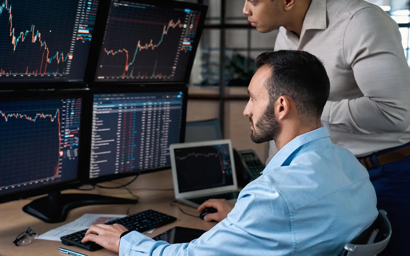 Two analysts looking at screens with data 