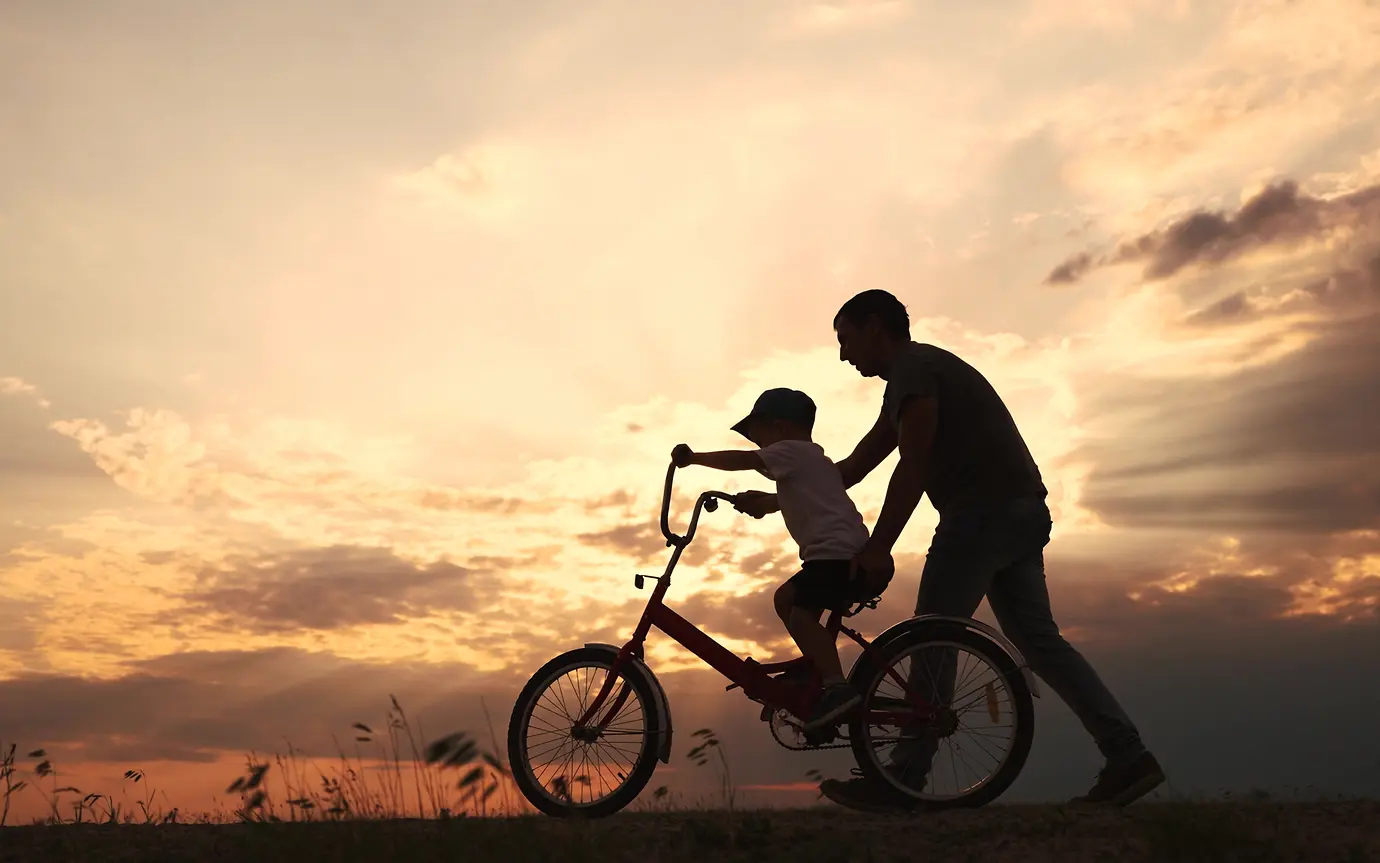 Parent helps child riding a bike