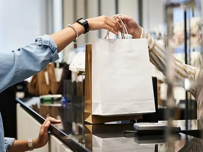 Women receiving shopping purchase in bag at till