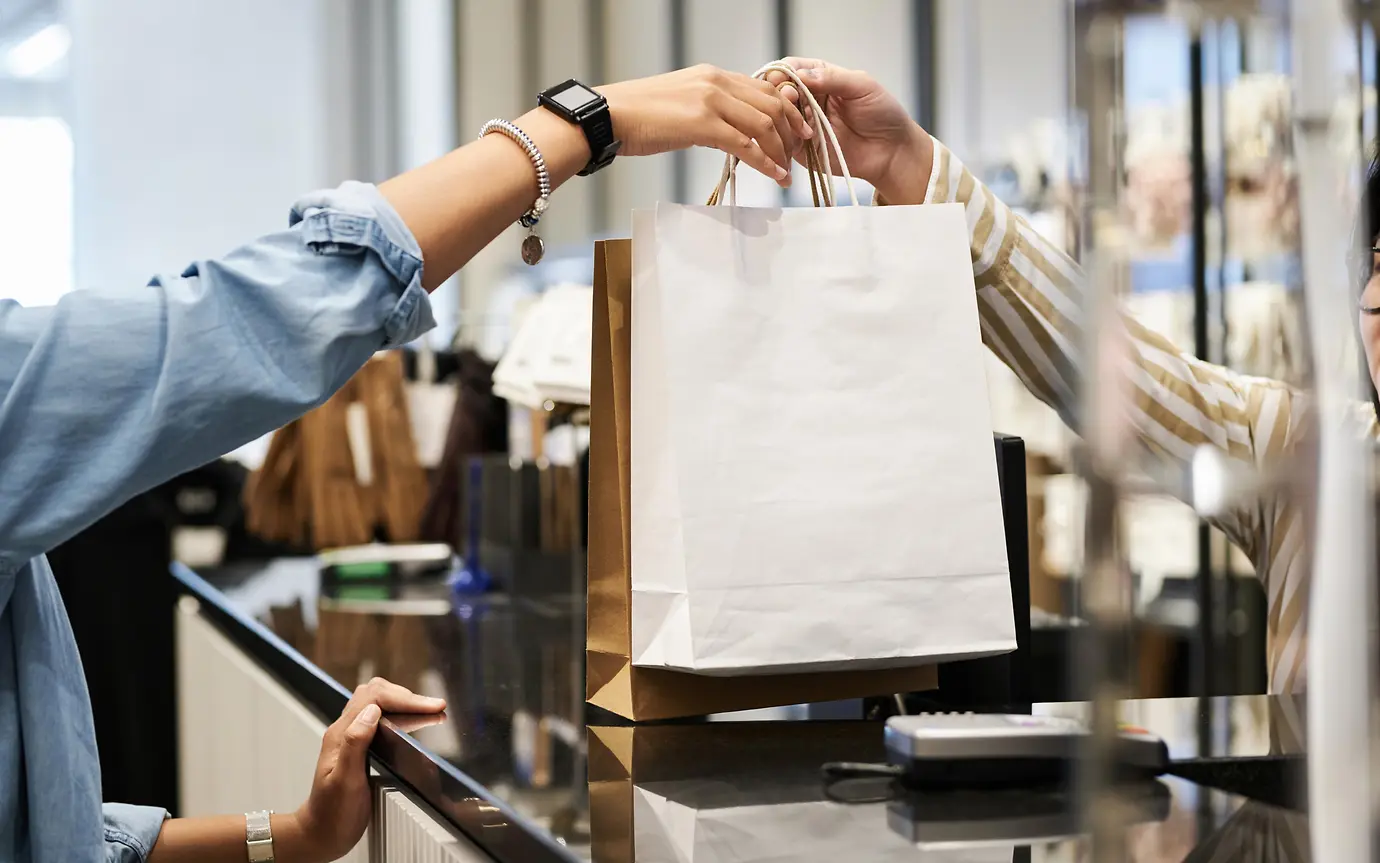 Women receiving shopping purchase in bag at till