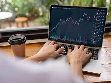 Hand of woman in coffee shop using laptop check, look graph on monitor screen for buy or sell on stock exchange market. 