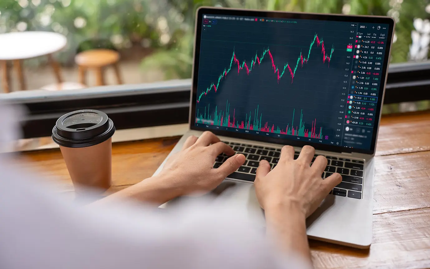 Hand of woman in coffee shop using laptop check, look graph on monitor screen for buy or sell on stock exchange market. 